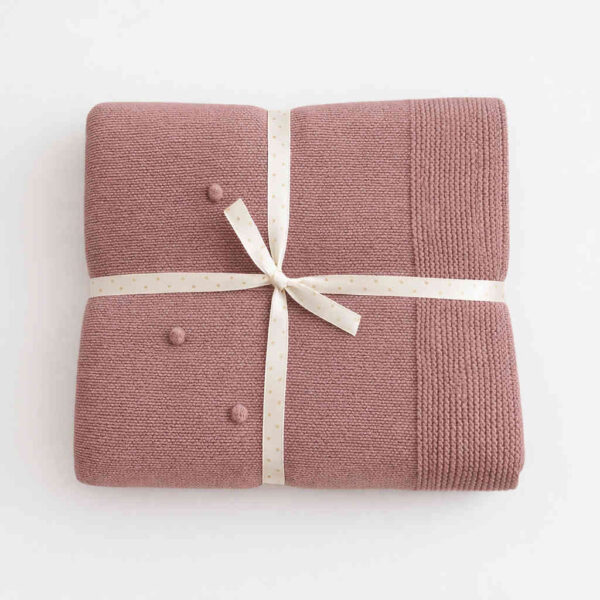 Couverture bébé rose pliée avec ruban blanc