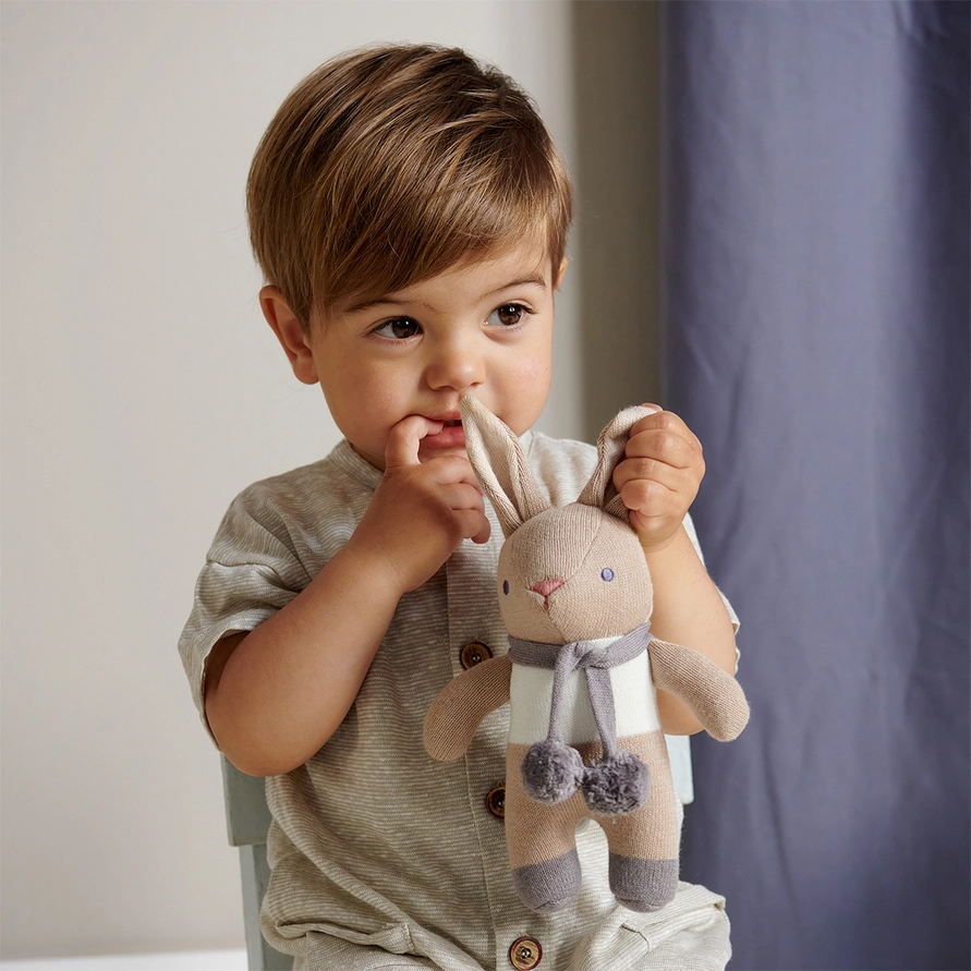 Enfant tenant le hochet lapin taupe et gris Baby Threads.