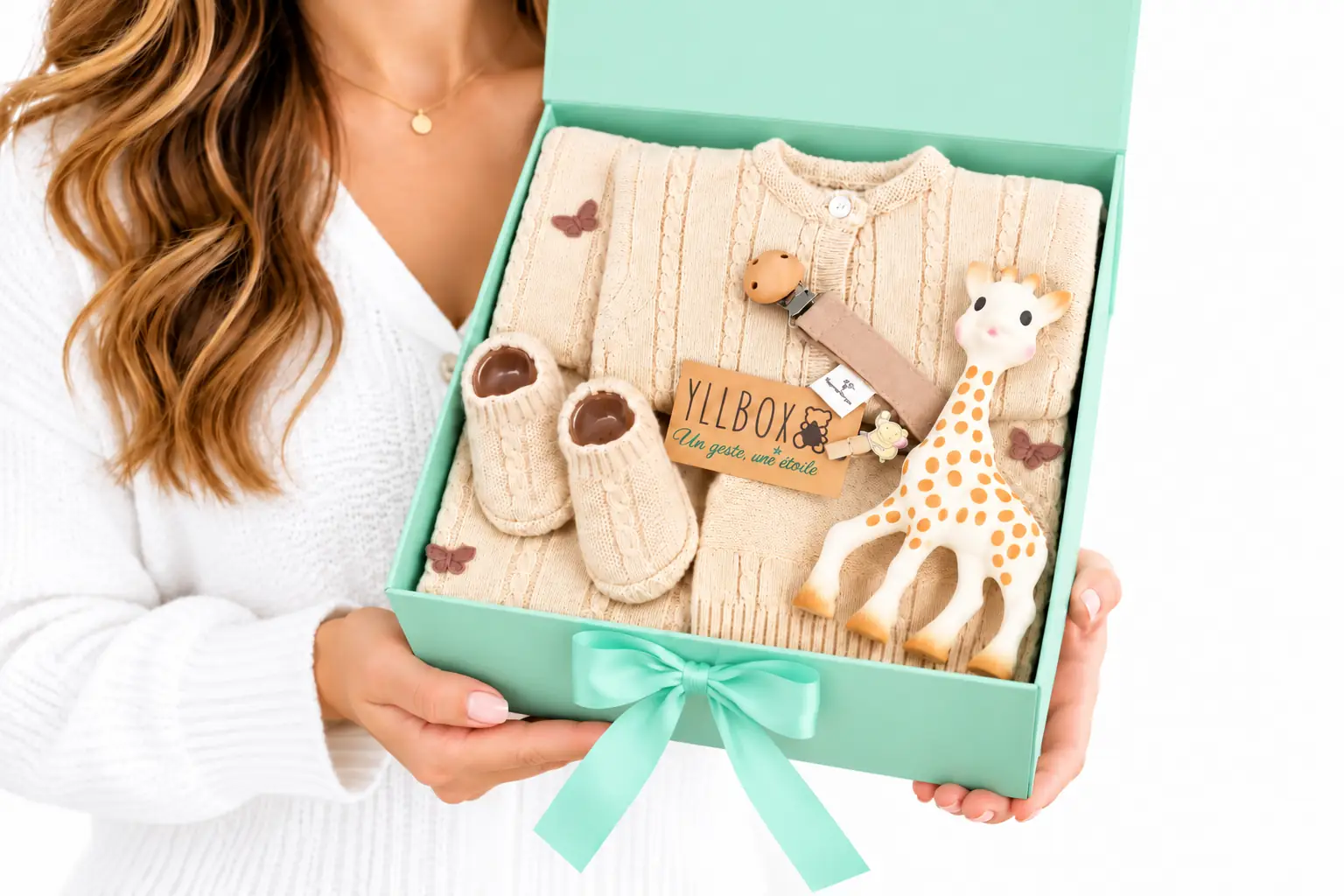 Femme tenant un coffret naissance YllBox vert avec vêtements et accessoires pour bébé